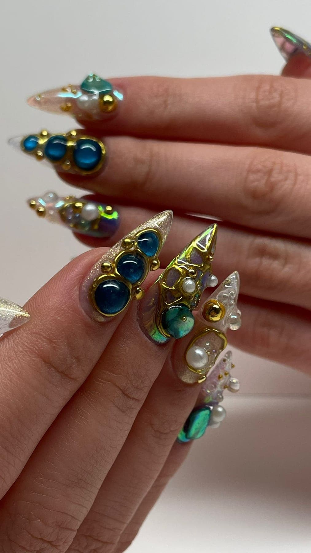 Stiletto doré, cristaux bleus et perles posées comme bijoux.